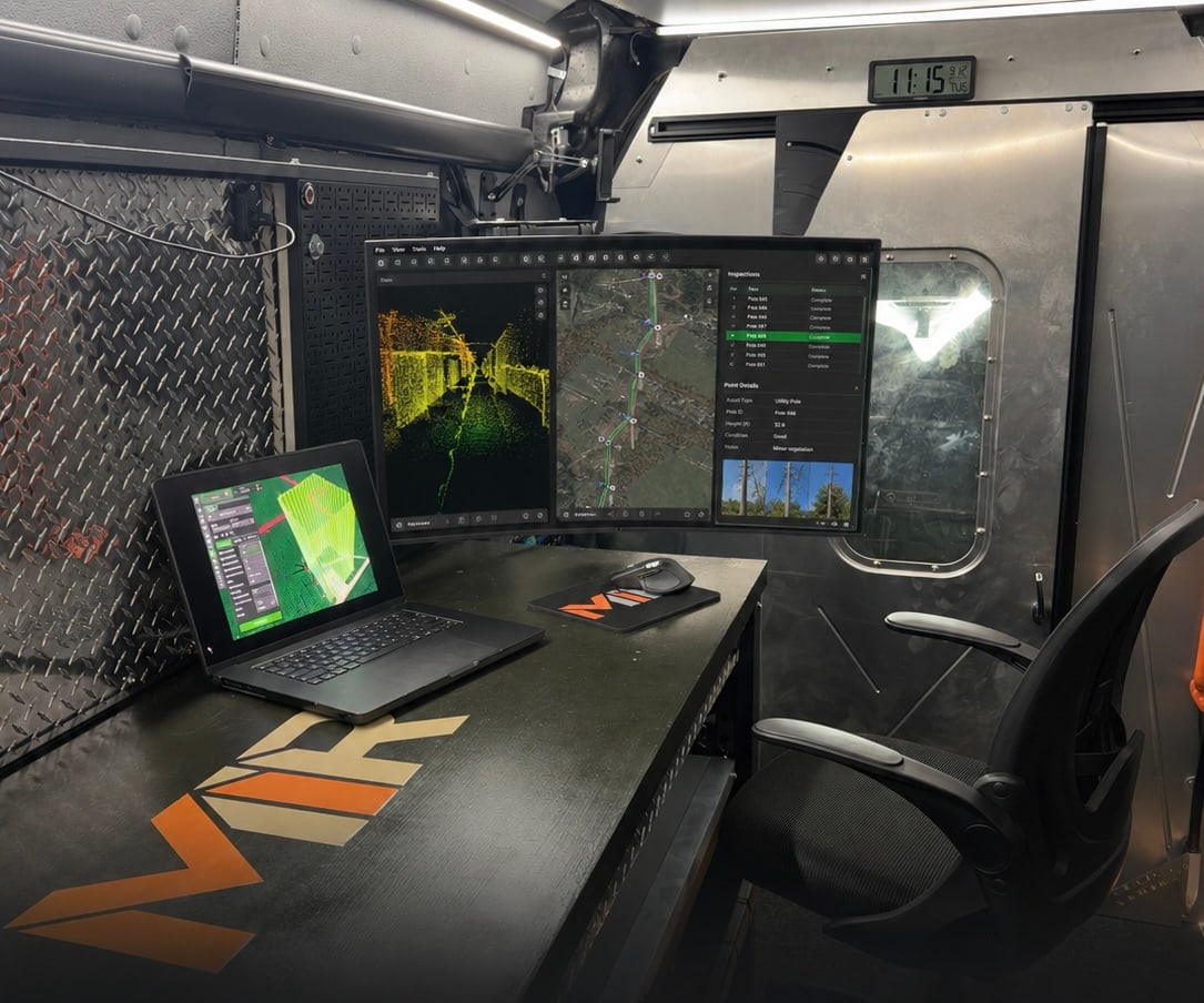 Interior of the MIR command van showing a dual-monitor and laptop workstation reviewing LiDAR point-cloud and inspection data at the MIR-branded desk