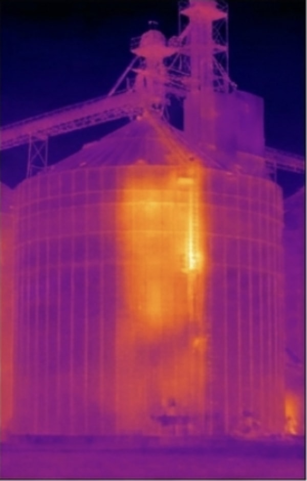 Thermal frame of the same steel bin showing the warm grain-mass and moisture signature inside