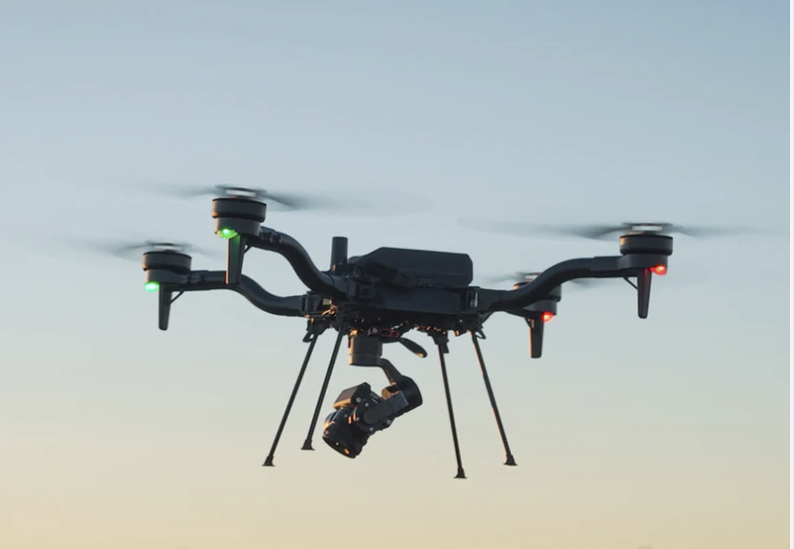 MIR survey drone with a gimbal-mounted camera in flight at dusk, capturing exterior imagery of a grain facility