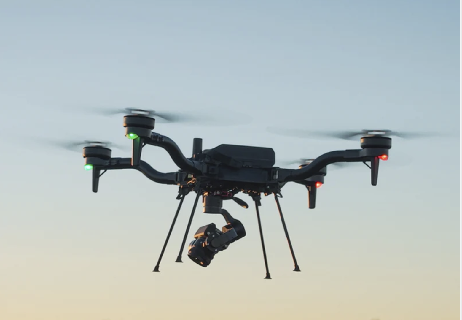 American-made Freefly Astro drone with a gimbal-mounted camera flying an autonomous rail-corridor capture pass at dusk