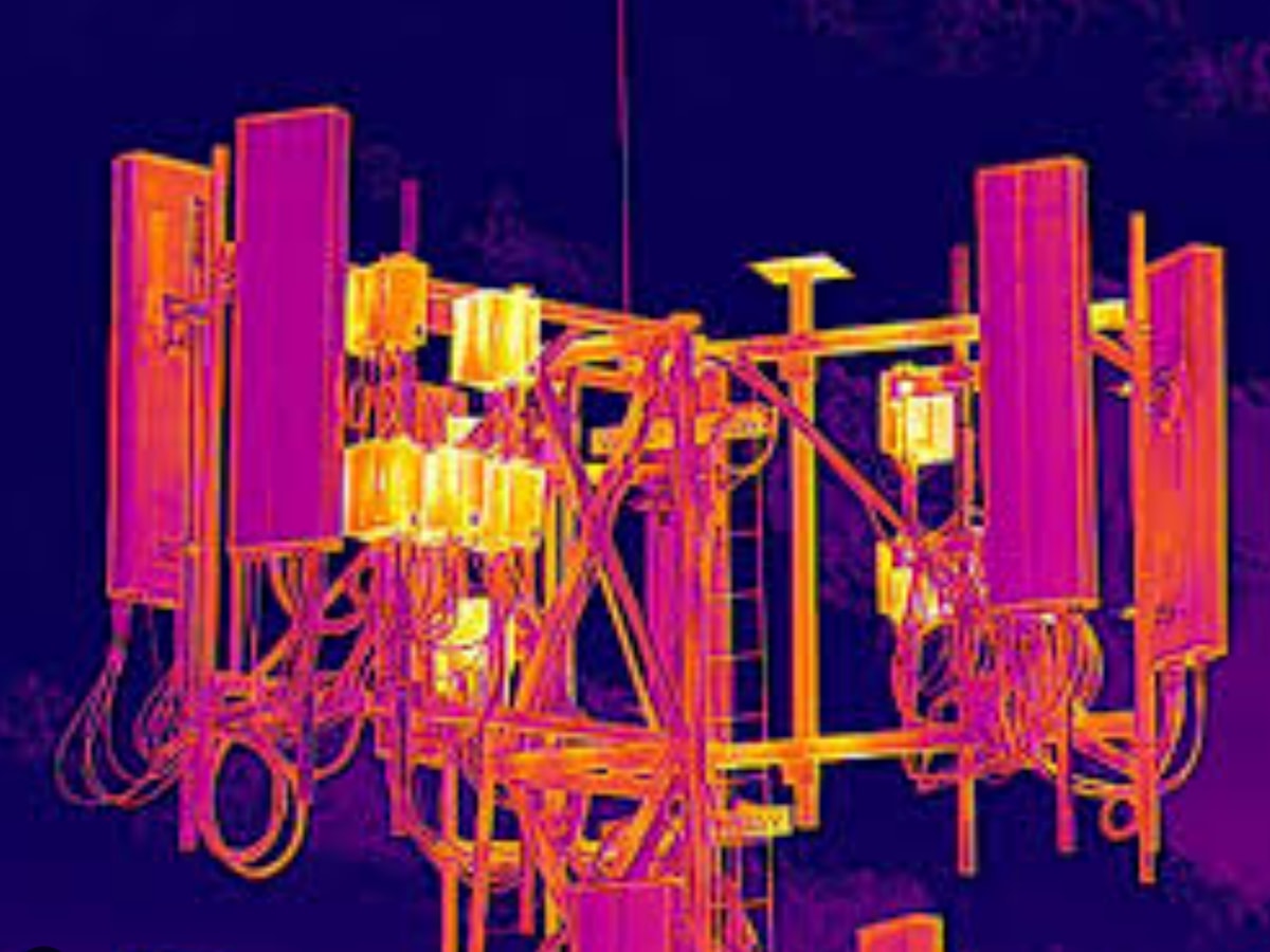 Radiometric thermal aerial frame of a cell tower head, with remote radio units and jumper connections glowing hot against the cooler steel and antennas