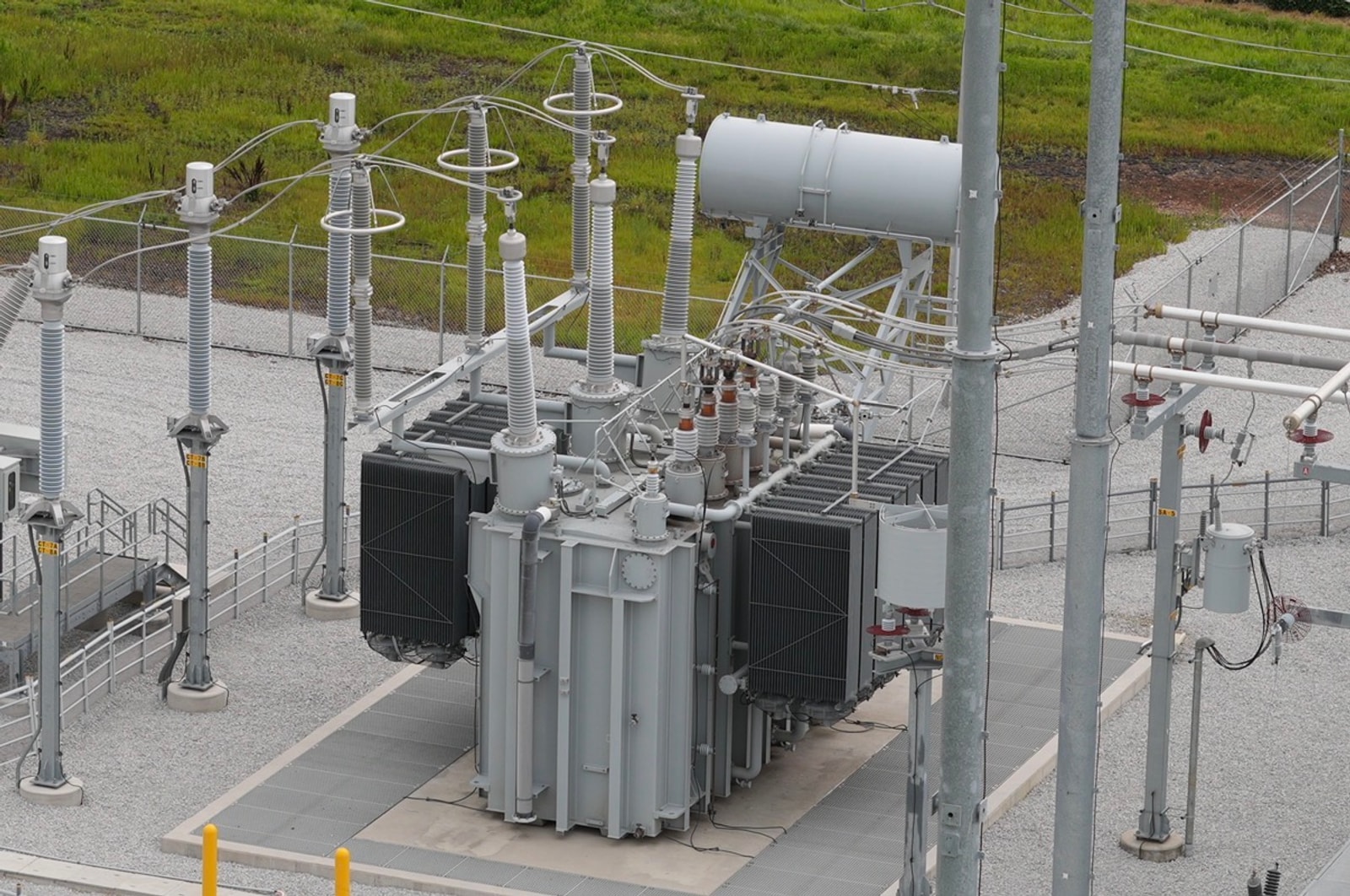 High-resolution daylight RGB aerial of a power substation — main transformer, radiator banks, bushings, and insulator stacks in sharp visible detail